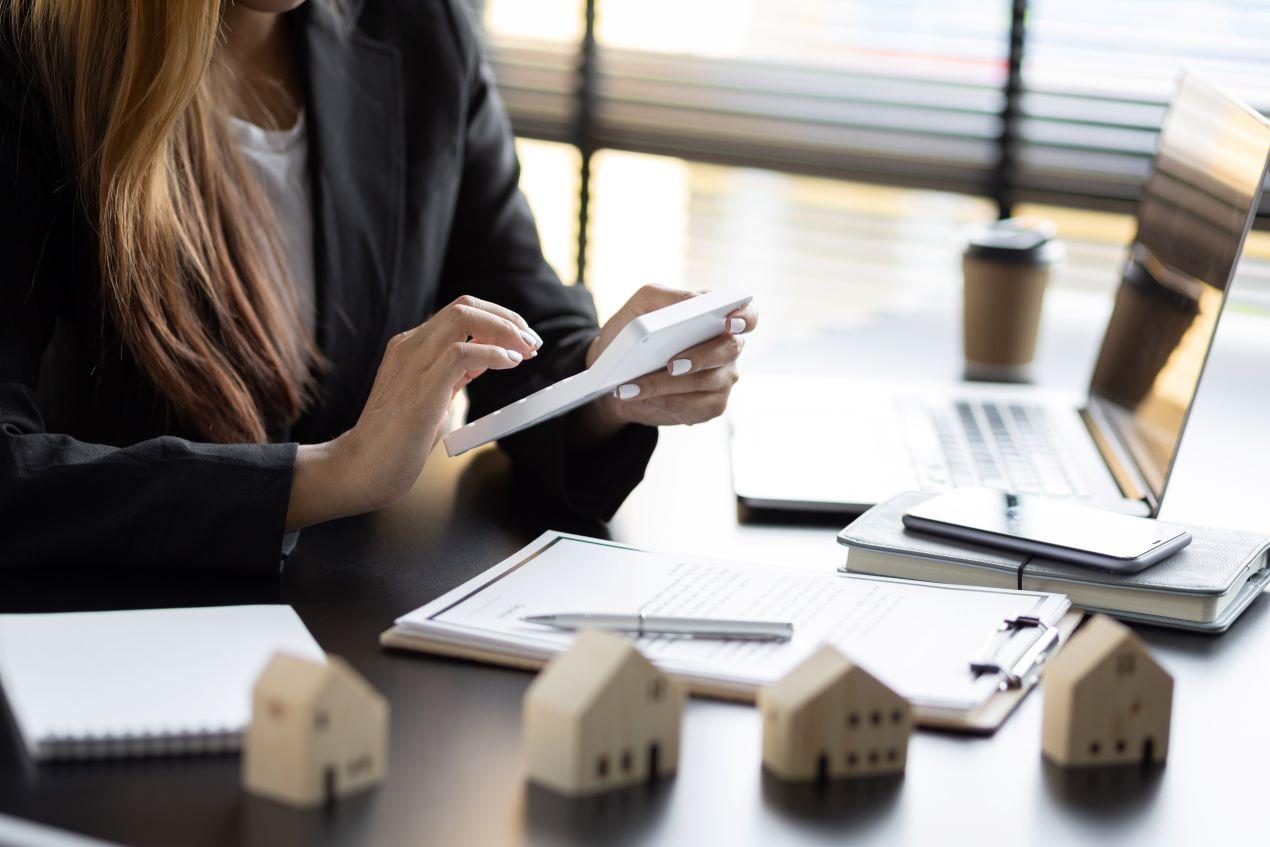 Immobiliengutachterin arbeitet mit Unterlagen, Tablet und Modellhäusern am Schreibtisch – Darstellung des Bewertungsprozesses in Stuttgart.