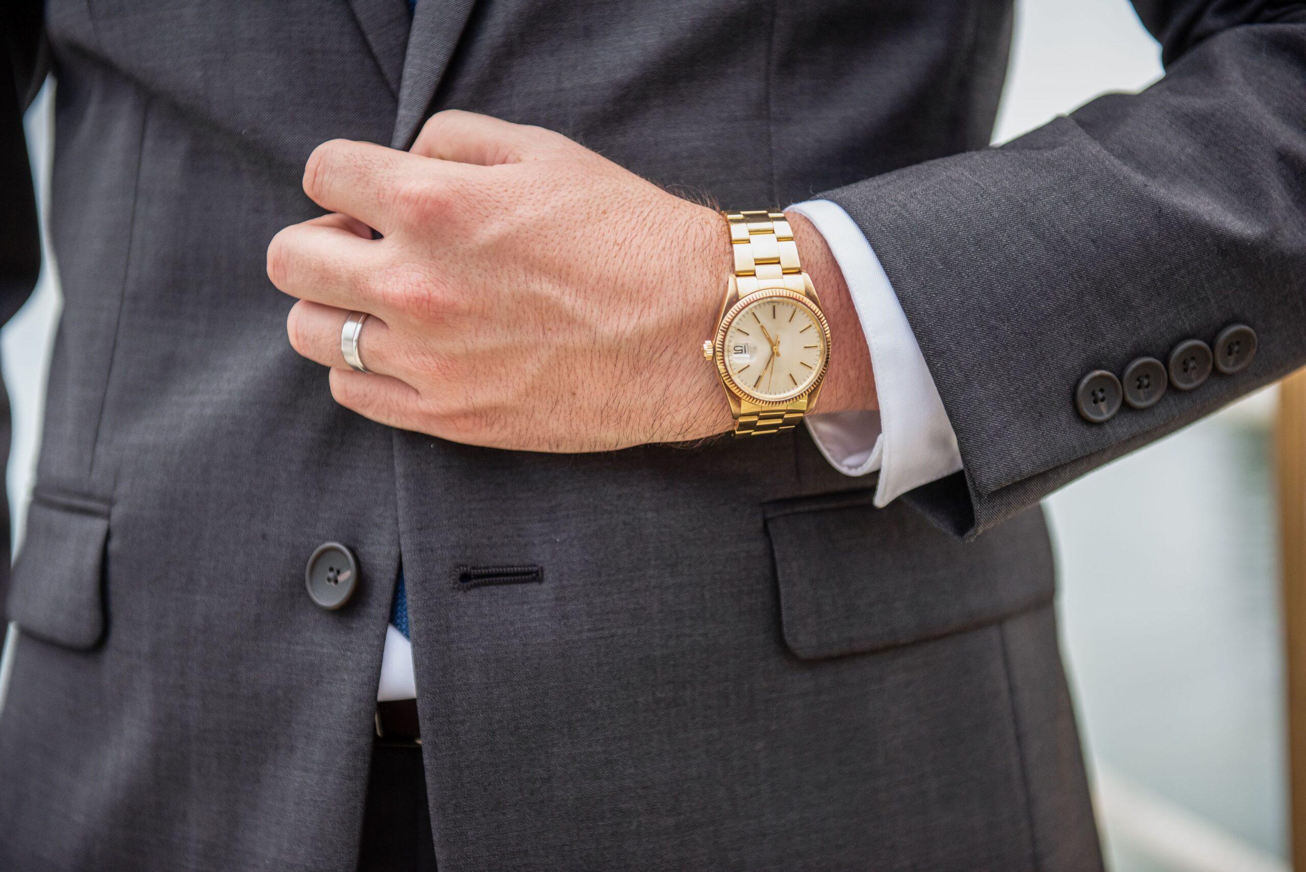 Mann mit Anzug trägt eine goldene Uhr.