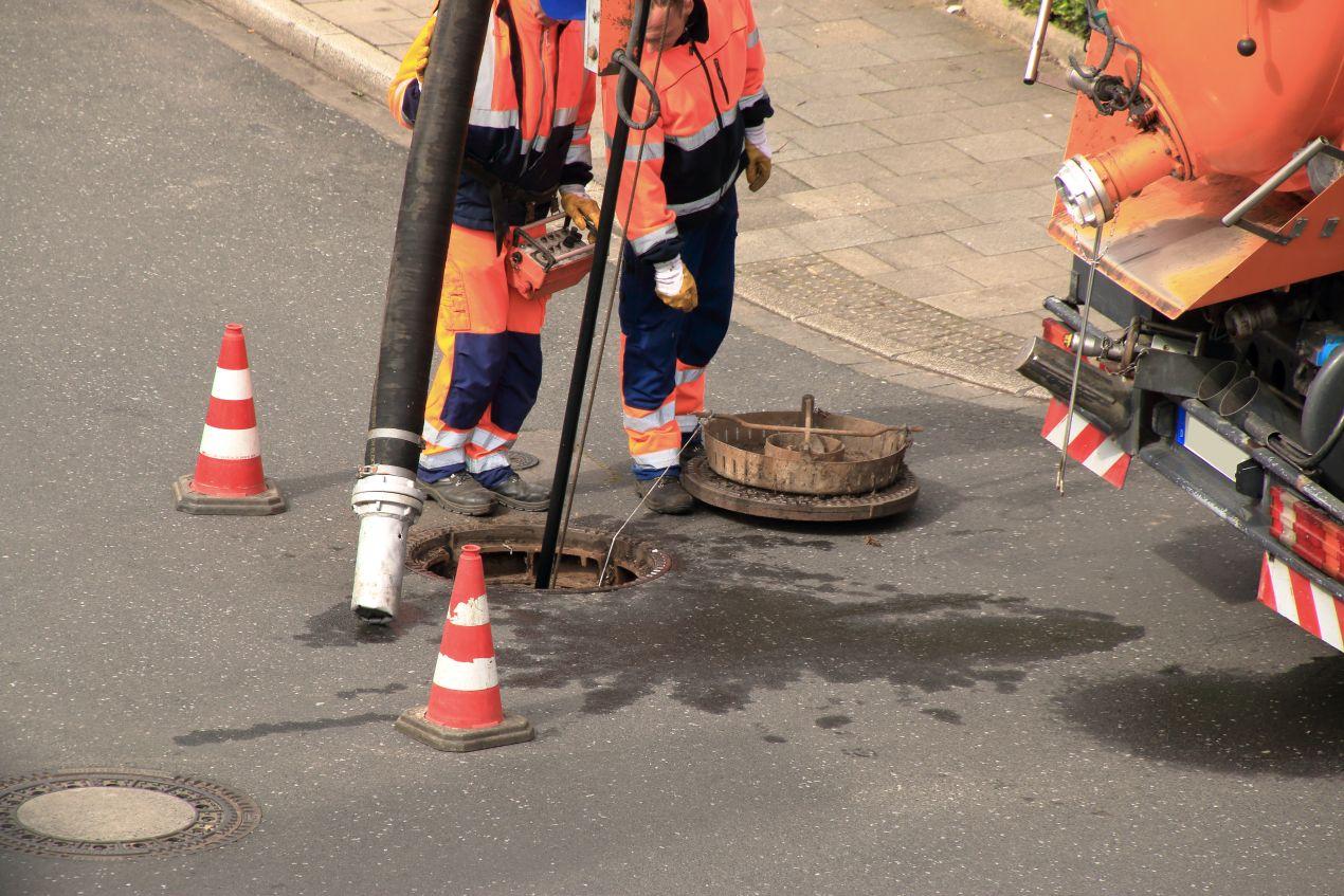 Bauarbeiter bei der Kanalsanierung mit grabenloser Methode an einem Schacht, um Verkehrsbehinderungen zu vermeiden