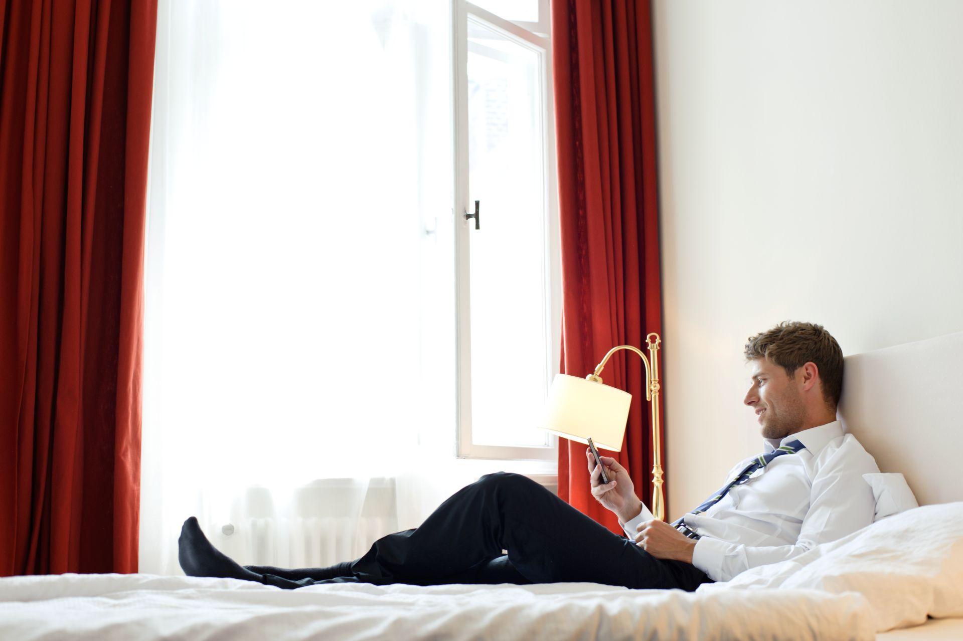 Geschaeftsreisender erfasst Belege mobil per Smartphone im Hotelzimmer